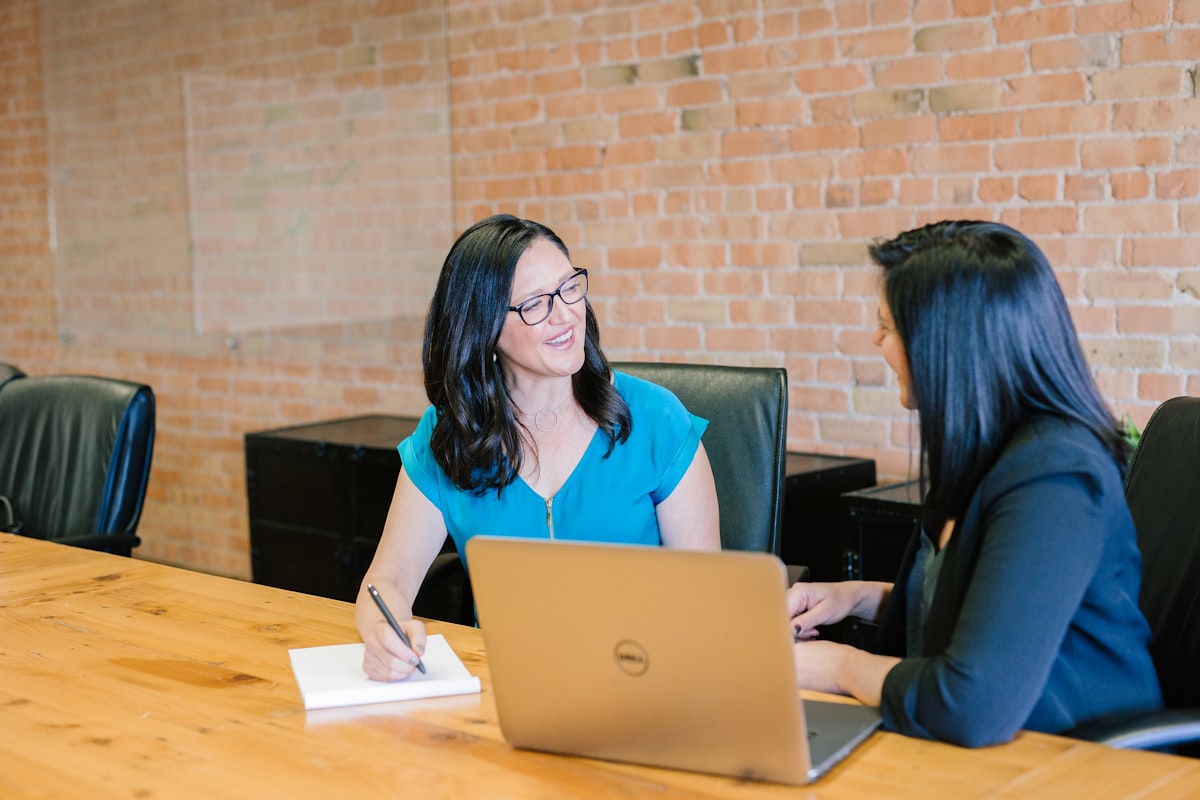 woman in teal t-shirt sitting beside woman in