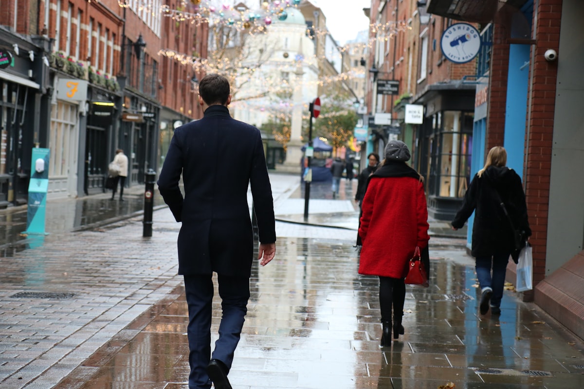 A man in a suit walking down a wet street