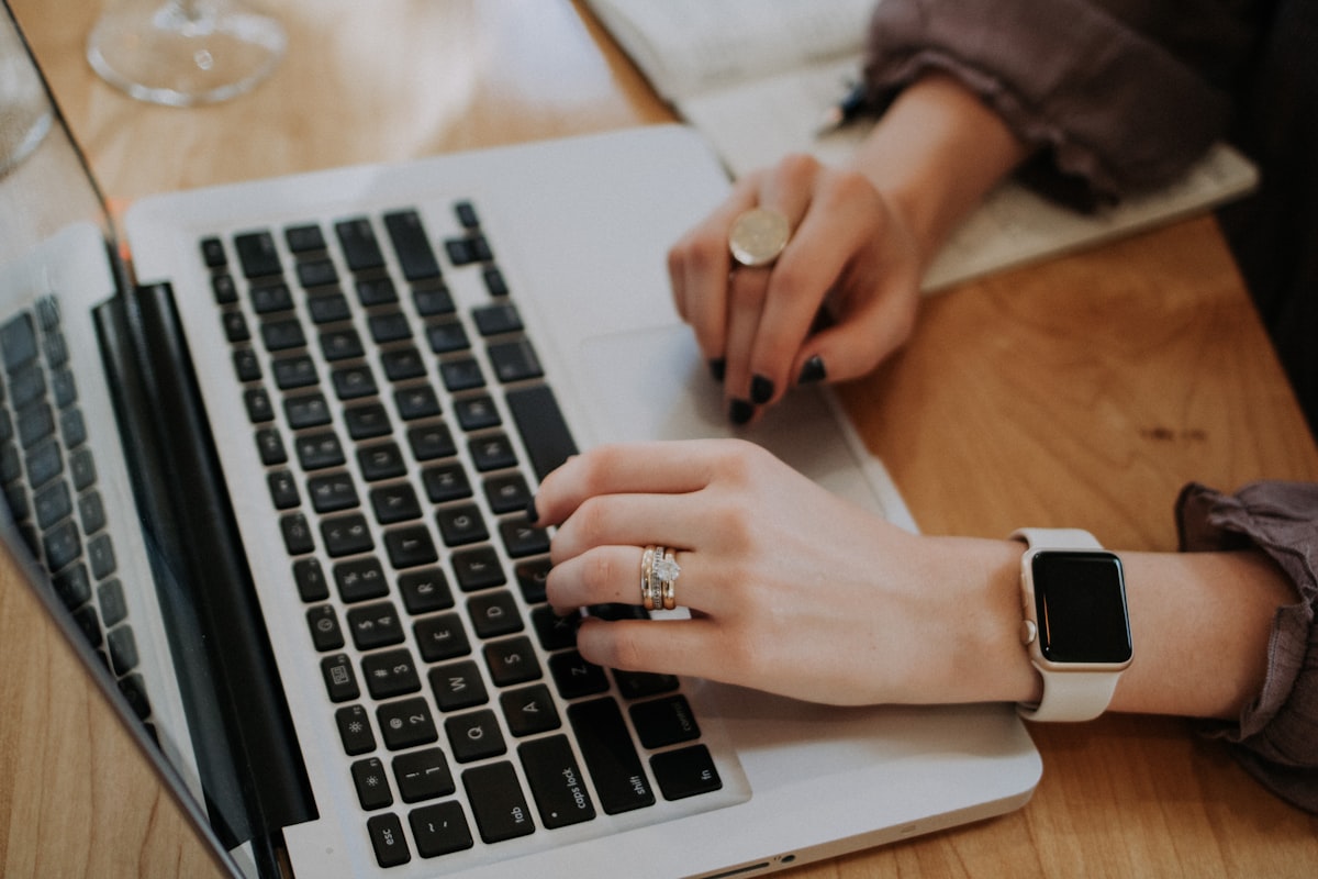 Hands working on a laptop at a wooden desk